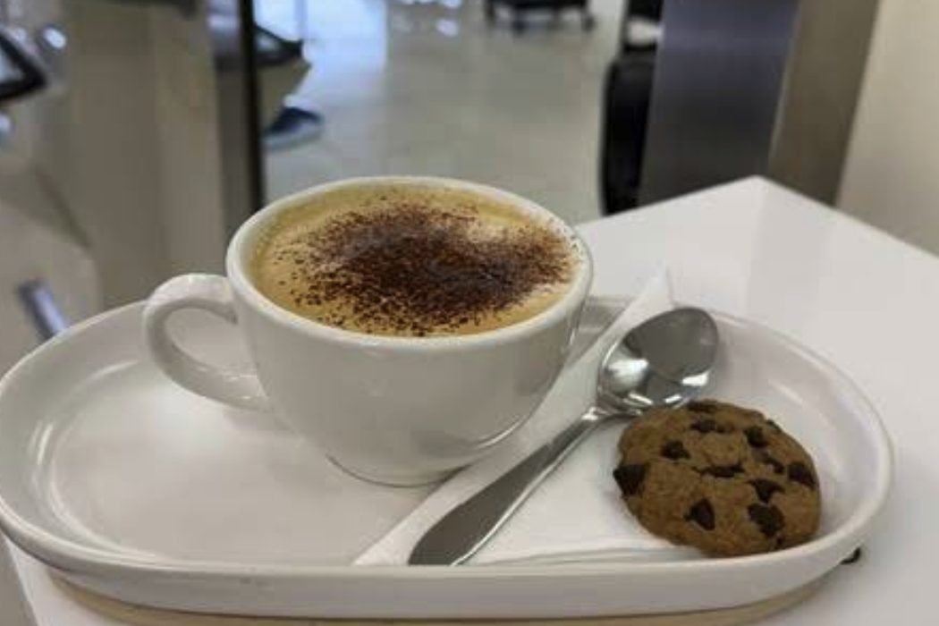 A cappuccino and a cookie on a saucer at the salon