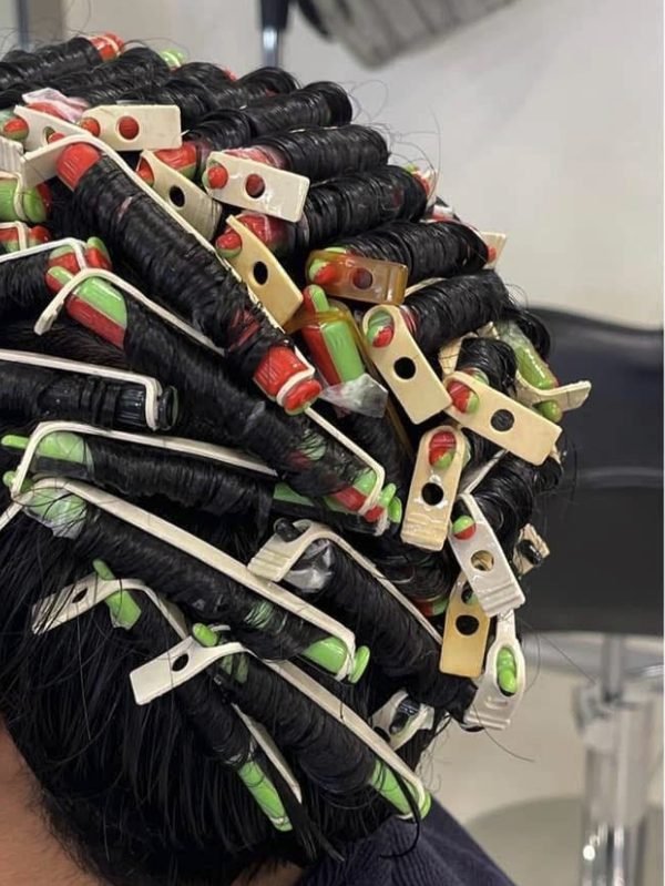 A client’s hair wound on perm rods during a perm